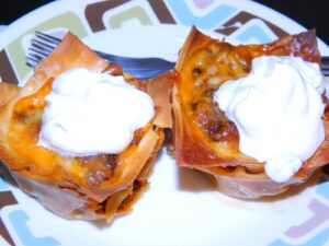 Taco cupcakes with sour cream on plate with fork